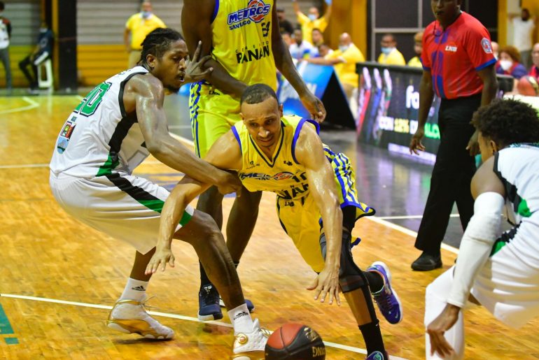 Adrís De León, de Metros, driblea entre los jugadors de Soles, Malik Pope y Kelvin Peña.