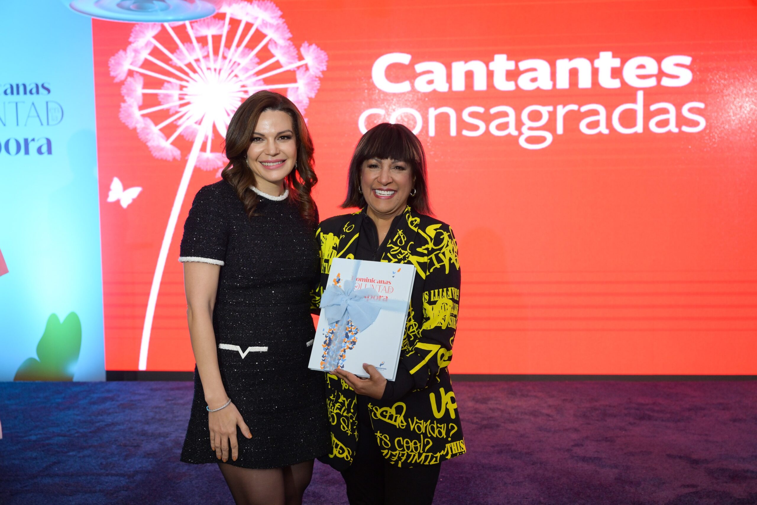 Noelia García de Pereyra, presidenta del Voluntariado Banreservas, reconoce a la cantante Milly Quezada, durante la presentación del libro “Dominicanas de Voluntad en la Diáspora”.